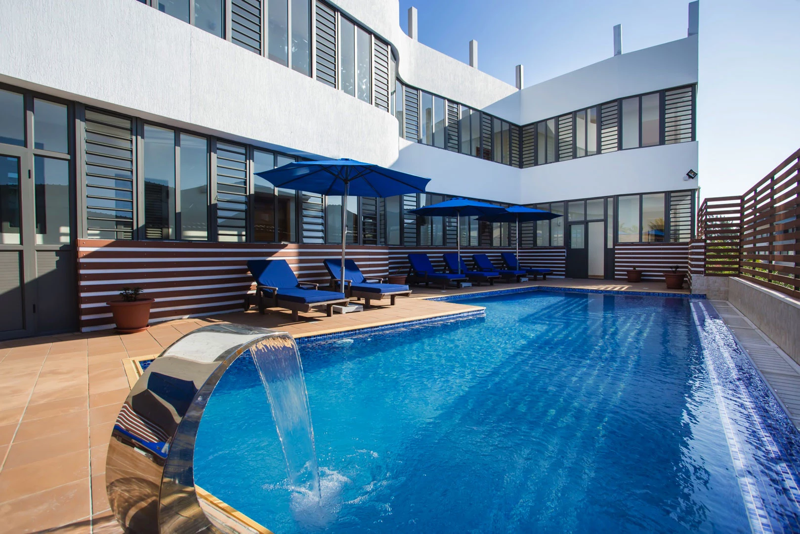 Residence Potosi apartment-hotel pool terrace with sun loungers and umbrellas.