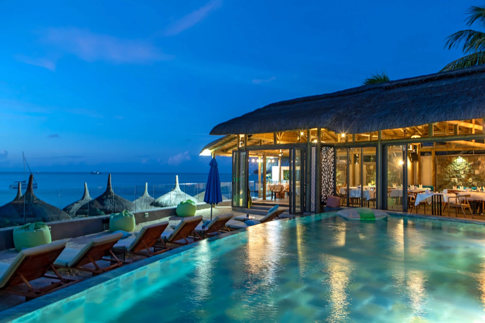 Wonders Beach Boutique at sunset with ocean view, poolside lounge, and outdoor dining.